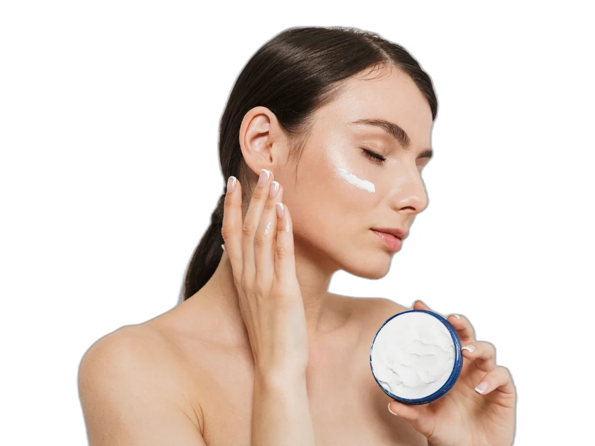 Woman applying cream to her cheek, holding a jar of moisturizer — medical skincare